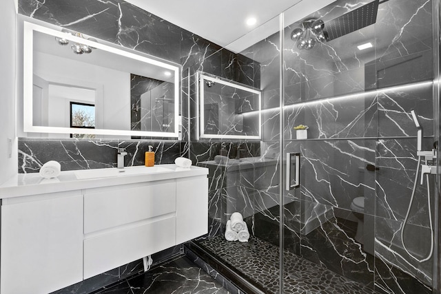 full bathroom featuring marble finish floor, a marble finish shower, tile walls, and vanity