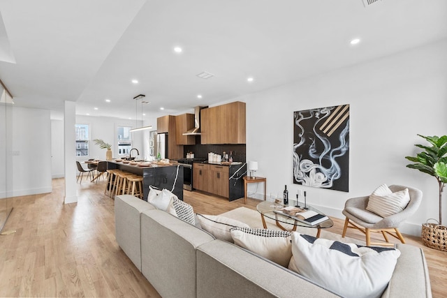 living area with baseboards, light wood-type flooring, and recessed lighting