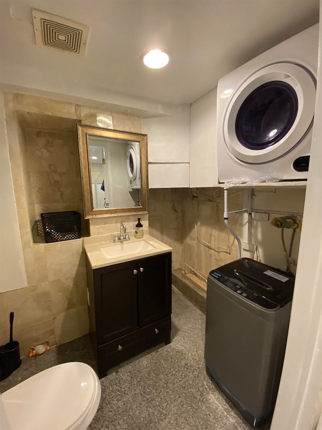 bathroom with toilet, vanity, tile walls, and washer / clothes dryer