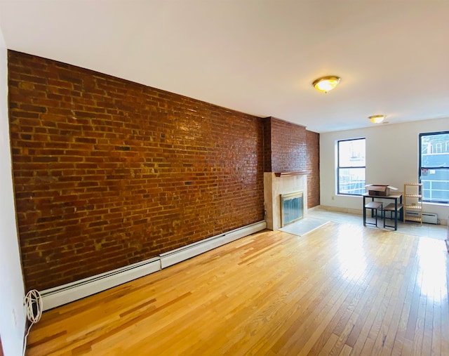 unfurnished living room featuring brick wall, light wood-type flooring, and a baseboard radiator