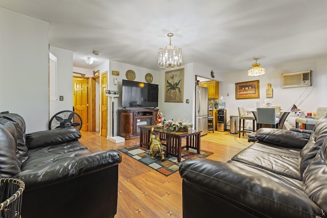 living room with a chandelier, a wall mounted AC, and light wood-style floors