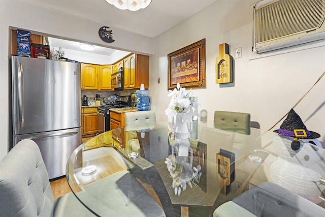 dining space with light wood finished floors and a wall mounted AC