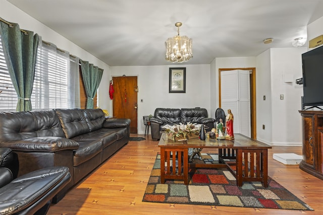 living area with baseboards, hardwood / wood-style flooring, and a notable chandelier