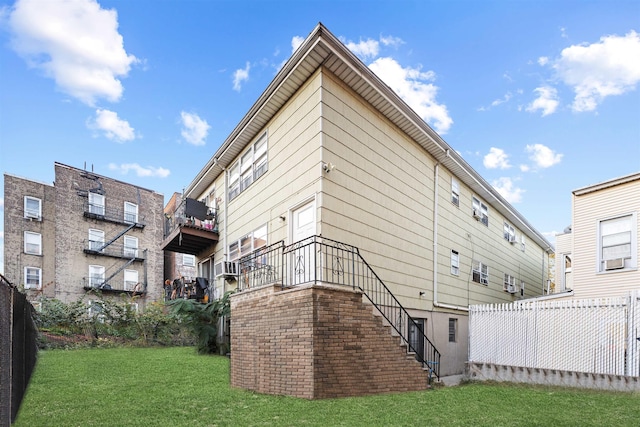 back of property with stairway, fence, and a lawn