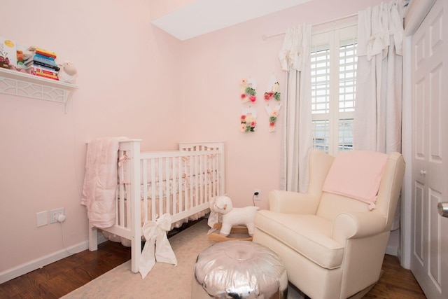 bedroom featuring a crib and dark wood-type flooring