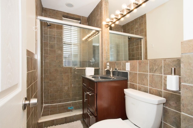 bathroom featuring an enclosed shower, vanity, toilet, and tile walls