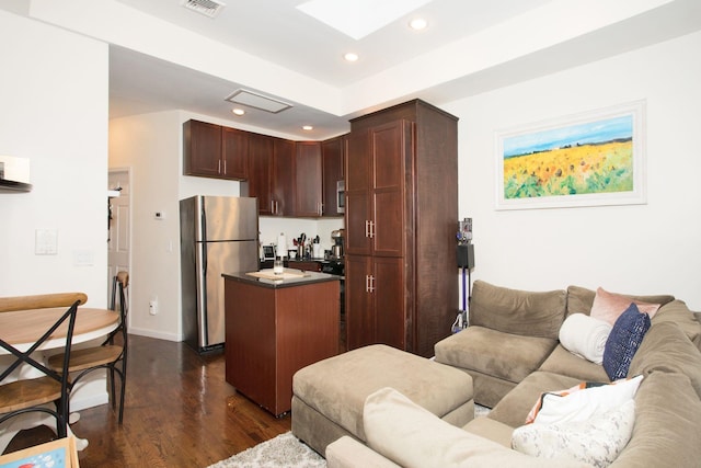 kitchen with dark hardwood / wood-style floors, a kitchen island, and stainless steel refrigerator