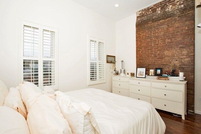 bedroom featuring brick wall and dark hardwood / wood-style floors