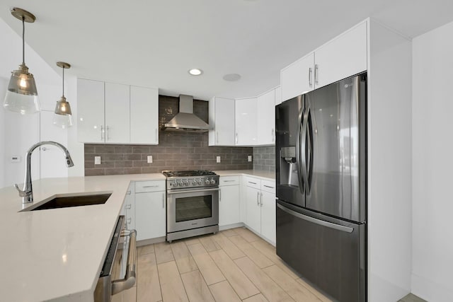 kitchen with a sink, light countertops, appliances with stainless steel finishes, decorative backsplash, and wall chimney exhaust hood