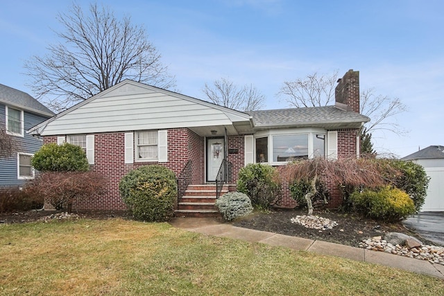 view of front facade featuring a chimney, a front yard, brick siding, and a garage