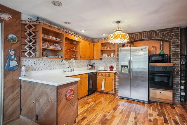kitchen with light wood finished floors, a sink, open shelves, brown cabinetry, and black appliances