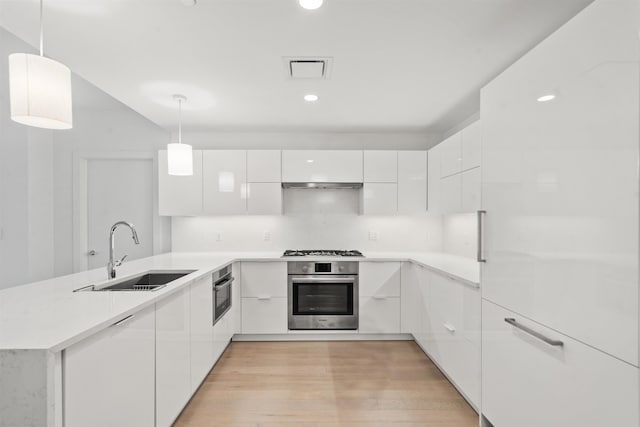 kitchen with stainless steel oven, sink, hanging light fixtures, and white cabinets