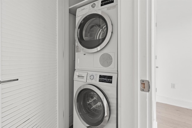 washroom with stacked washer and clothes dryer and light hardwood / wood-style flooring