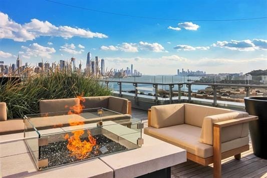 wooden terrace featuring a water view and an outdoor fire pit