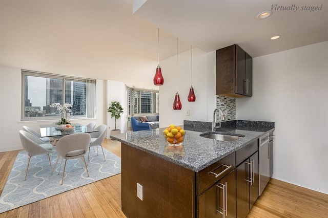 kitchen featuring tasteful backsplash, dark brown cabinets, sink, dark stone countertops, and dishwasher