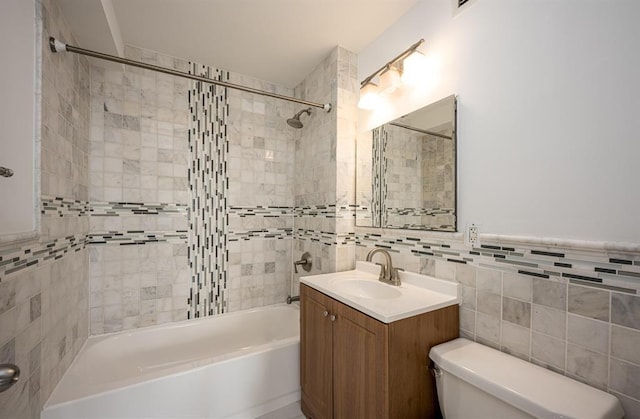 full bathroom featuring vanity, toilet, tiled shower / bath, and tile walls