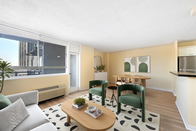 living room featuring a wall mounted air conditioner, light hardwood / wood-style floors, and a textured ceiling