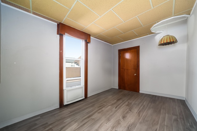 spare room featuring a drop ceiling and hardwood / wood-style flooring