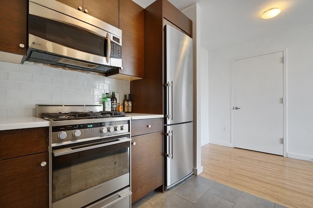 25 Mcwilliams Pl Unit 402, Jersey City, NJ 07302 - kitchen with baseboards, light countertops, tasteful backsplash, light tile patterned floors, and stainless steel appliances