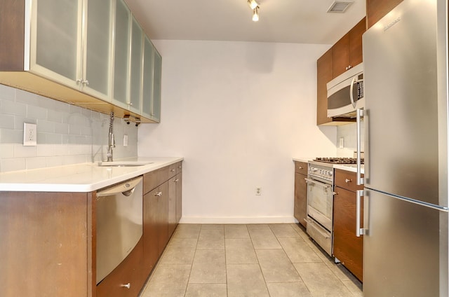 25 Mcwilliams Pl Unit 402, Jersey City, NJ 07302 - kitchen with appliances with stainless steel finishes, light tile patterned flooring, light countertops, glass insert cabinets, and brown cabinets