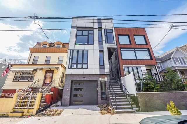 91 Pearsall Ave Unit 2, Jersey City, NJ 07305 - view of front of house with stucco siding, stairs, brick siding, an attached garage, and driveway