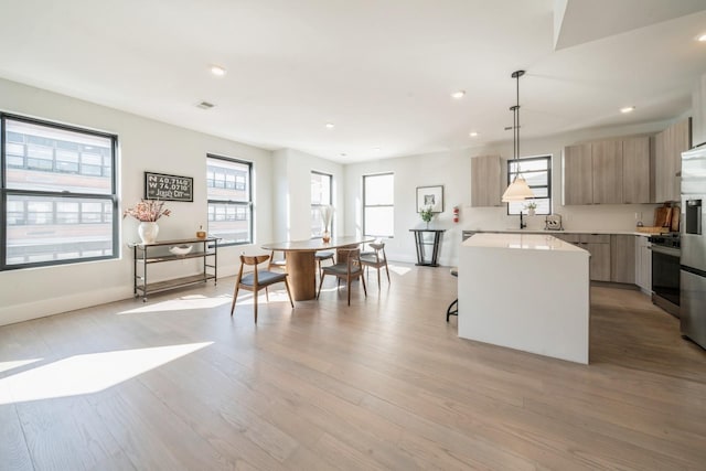 kitchen featuring light hardwood / wood-style flooring, light brown cabinetry, decorative light fixtures, a kitchen island, and stainless steel appliances