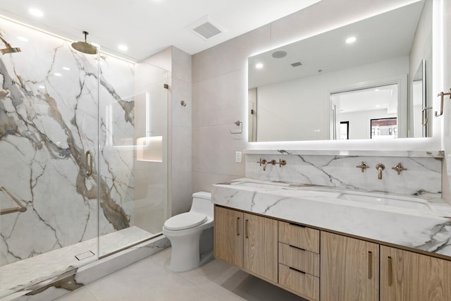 bathroom with double vanity, toilet, a marble finish shower, visible vents, and tasteful backsplash