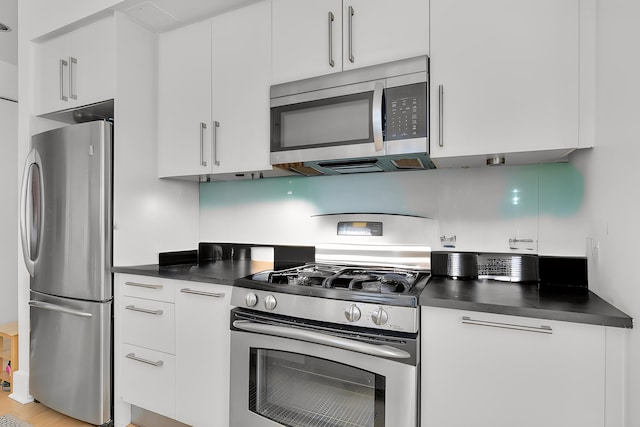 kitchen with dark countertops, appliances with stainless steel finishes, and white cabinetry