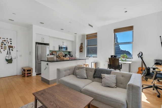 living area with recessed lighting, visible vents, and light wood-style flooring