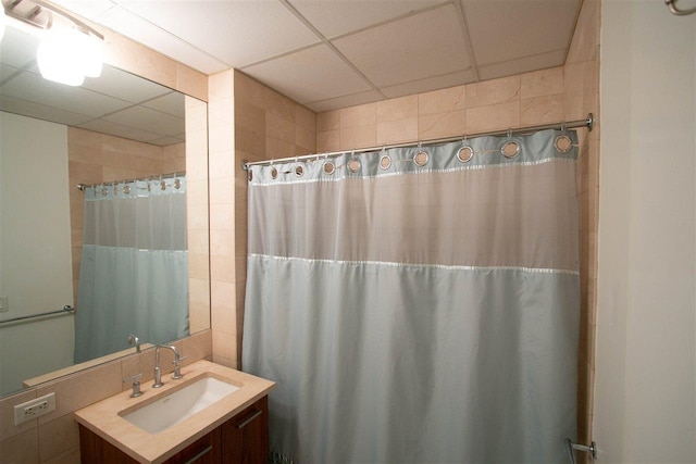 full bath with tile walls, vanity, a paneled ceiling, and a shower with curtain