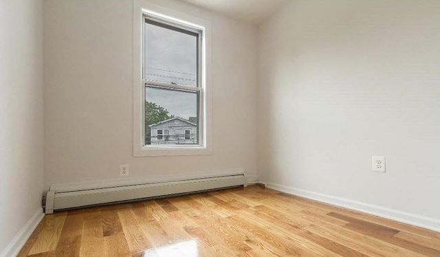 spare room with baseboard heating and light hardwood / wood-style floors