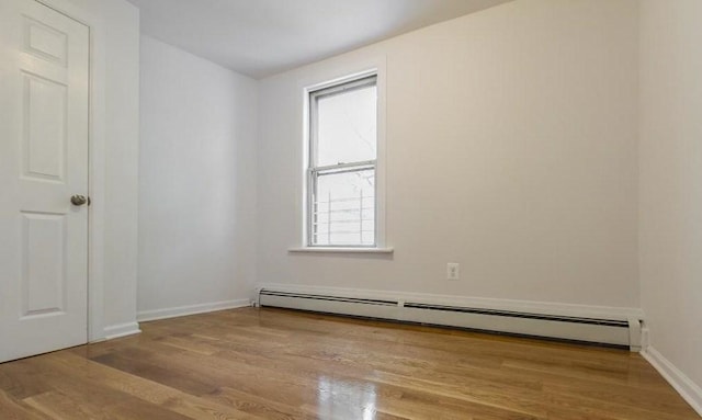 empty room with a baseboard heating unit and light hardwood / wood-style floors