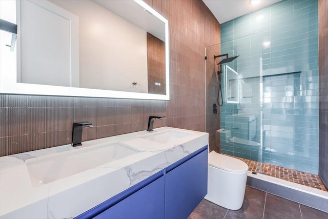 bathroom featuring double vanity, toilet, a sink, walk in shower, and tile walls