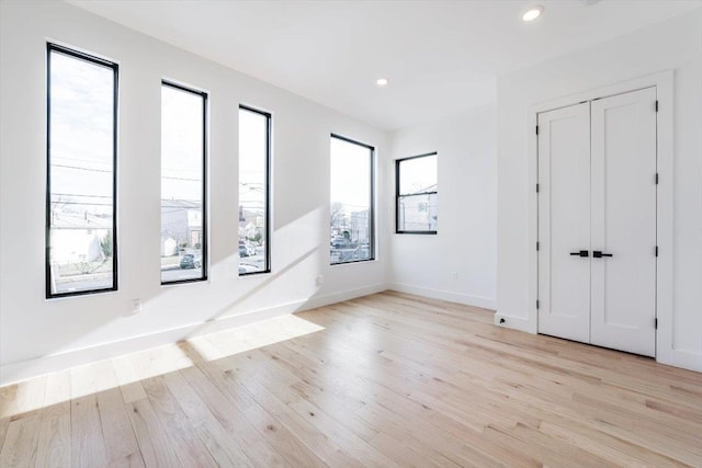 empty room featuring baseboards, light wood finished floors, and recessed lighting