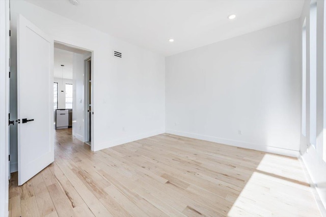 empty room featuring light wood-type flooring, baseboards, visible vents, and recessed lighting