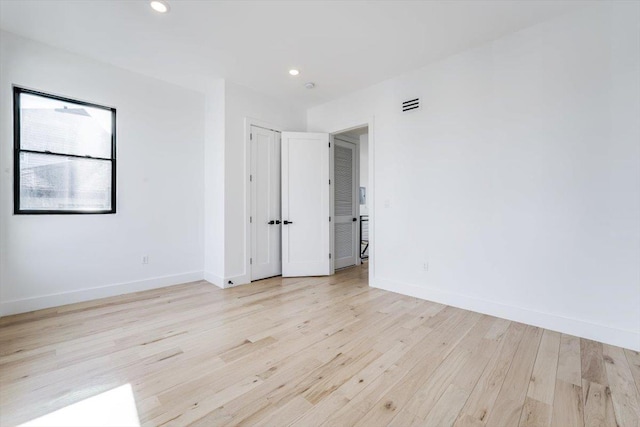 spare room with light wood-style floors, recessed lighting, visible vents, and baseboards