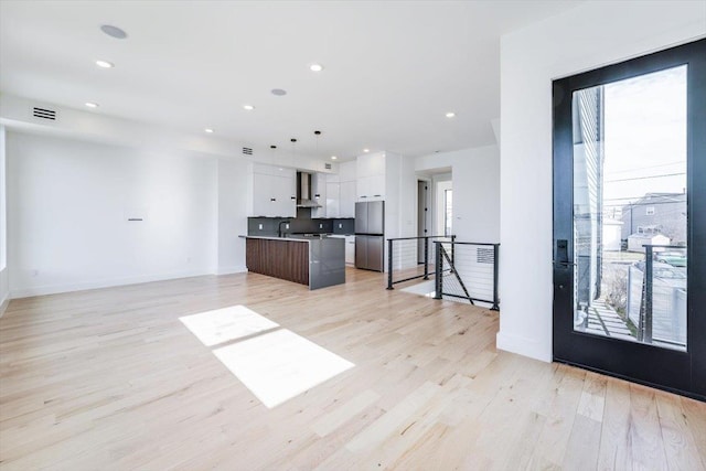 kitchen featuring light wood-style floors, freestanding refrigerator, white cabinetry, modern cabinets, and wall chimney exhaust hood