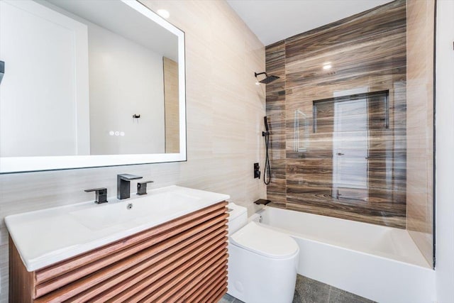 full bathroom featuring toilet, vanity, tile walls, and shower / bathtub combination