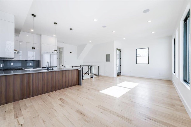 kitchen with decorative backsplash, white cabinets, a sink, modern cabinets, and light wood-type flooring