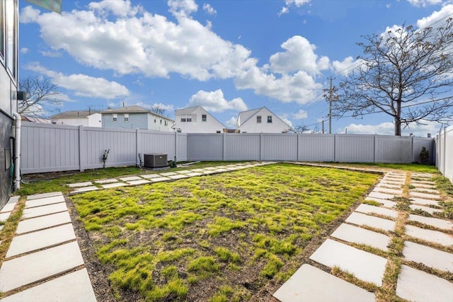 view of yard with a fenced backyard and central AC unit