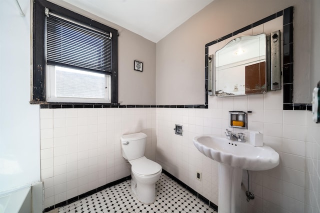 bathroom with toilet and tile walls