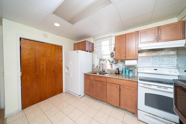 kitchen featuring sink, tasteful backsplash, light tile patterned floors, white appliances, and a drop ceiling