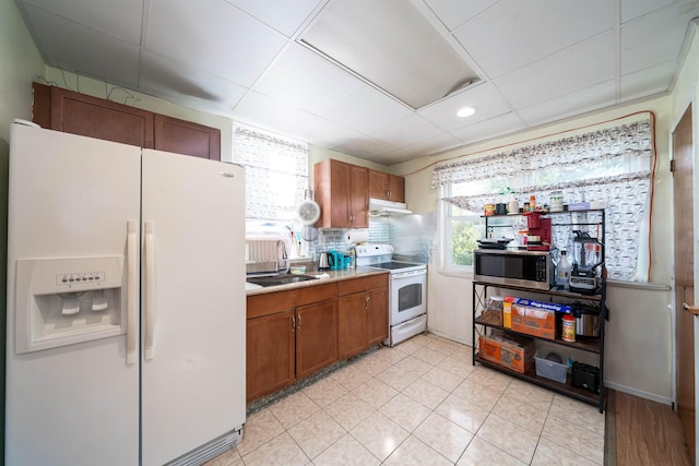 kitchen with a drop ceiling, sink, white appliances, and tasteful backsplash