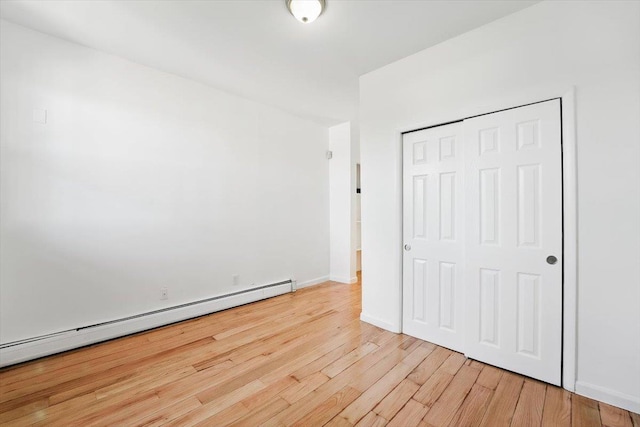 138 Leonard St Unit 2R, Jersey City, NJ 07307 - unfurnished bedroom featuring a baseboard heating unit, light wood-style floors, a closet, and baseboards