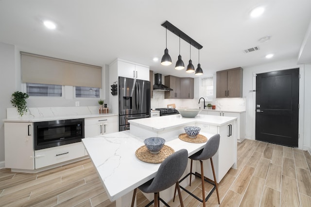 201 Zabriskie St Unit 1, Jersey City, NJ 07307 - kitchen with black appliances, wall chimney exhaust hood, light wood-style floors, a center island, and pendant lighting