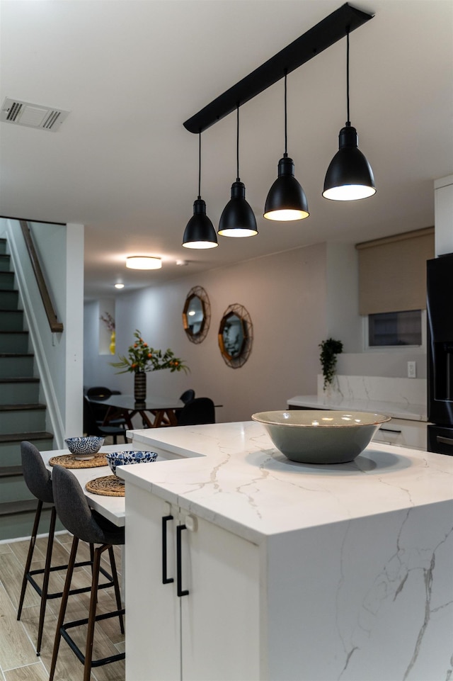 201 Zabriskie St Unit 1, Jersey City, NJ 07307 - kitchen featuring white cabinetry, hanging light fixtures, light stone counters, and a center island