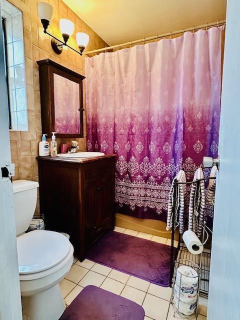 full bath featuring toilet, tile walls, vanity, and tile patterned flooring