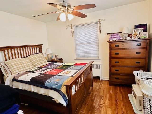 bedroom featuring a ceiling fan, wood finished floors, and radiator heating unit