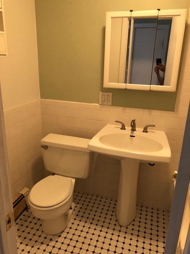 bathroom with tile walls, a wainscoted wall, toilet, and tile patterned flooring