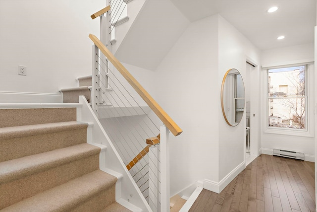 stairs featuring hardwood / wood-style flooring and a baseboard heating unit